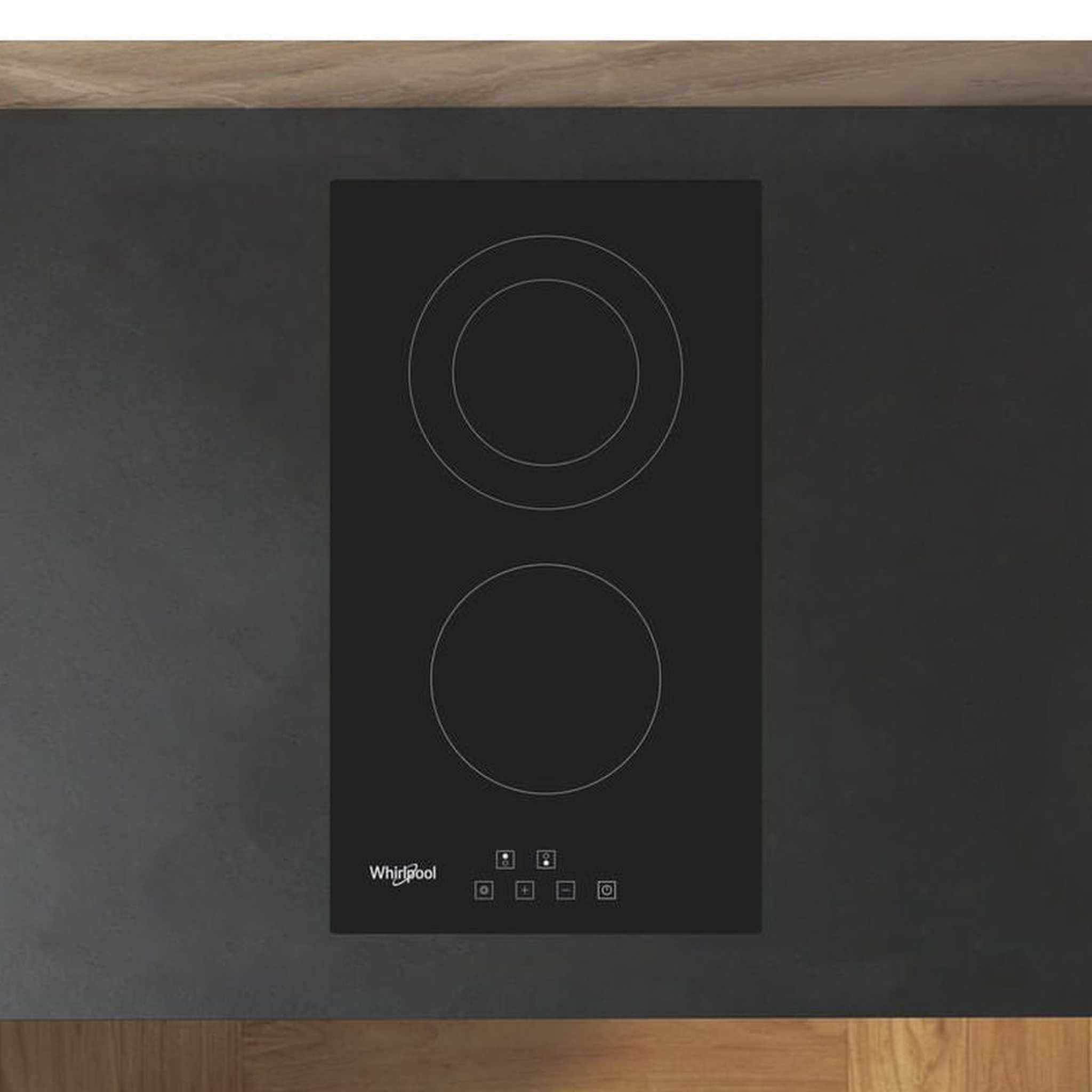 Una placa de inducción Whirlpool negra con dos zonas de cocción está empotrada en una encimera gris oscura.