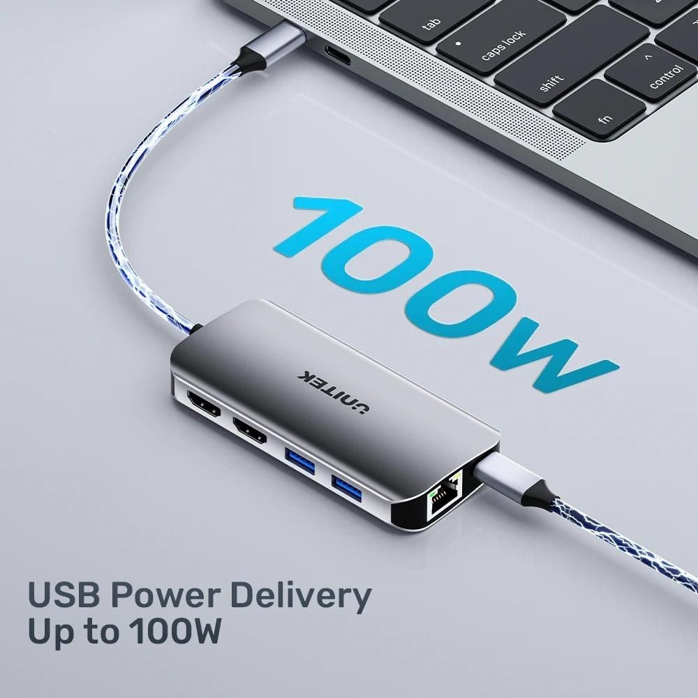 Srebrny hub USB-C z niebieskimi kablami jest podłączony do laptopa, tekst wskazuje 100W.