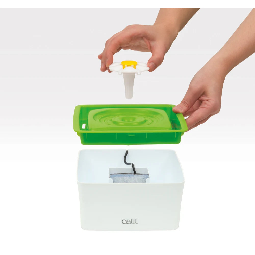 Persona ensamblando las piezas de una fuente para mascotas Catit blanca y verde.