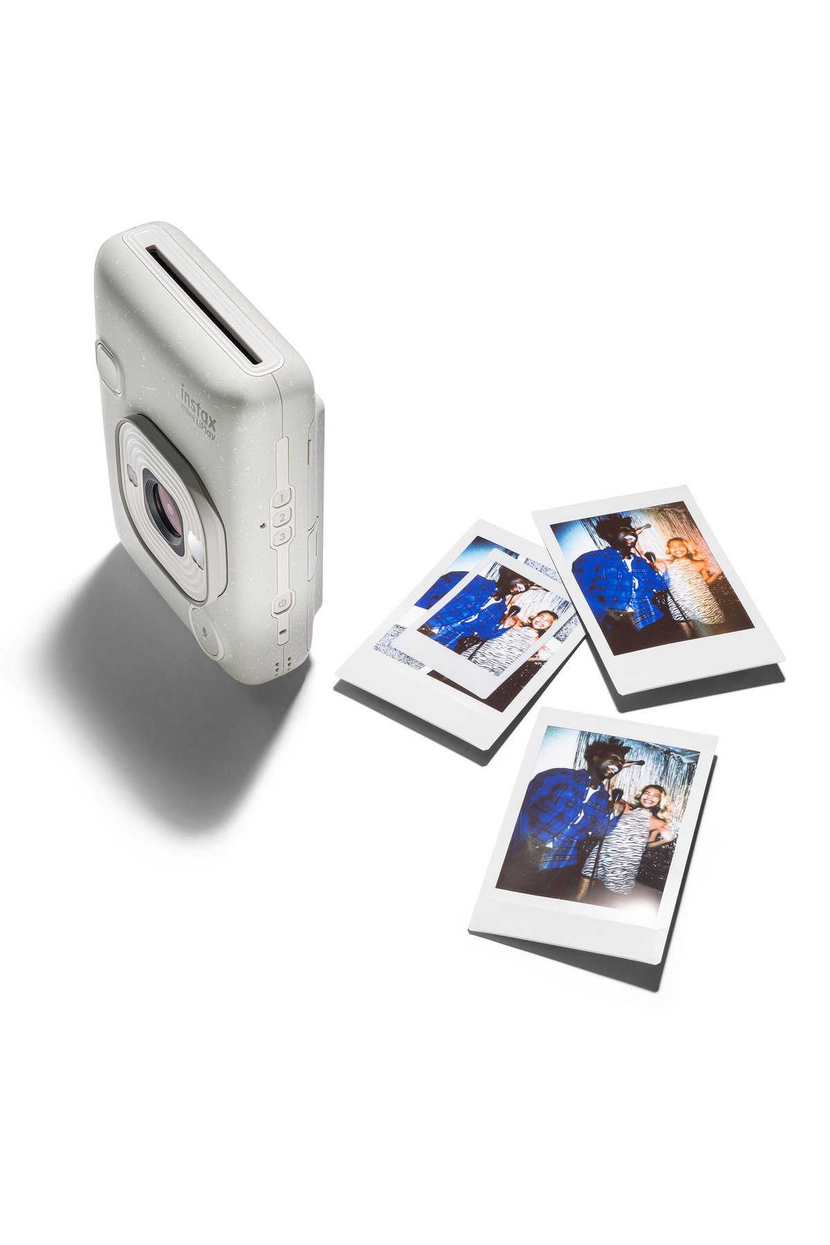 Beyaz arkaplanda  üç basılı fotoğrafla birlikte beyaz anlık fotoğraf makinesi.