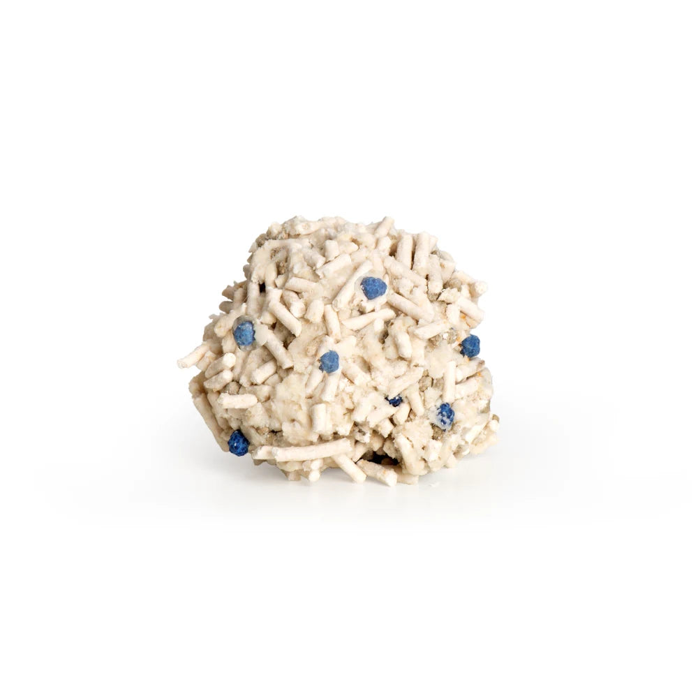 Una formación mineral beige con pequeños puntos azules sobre fondo blanco.