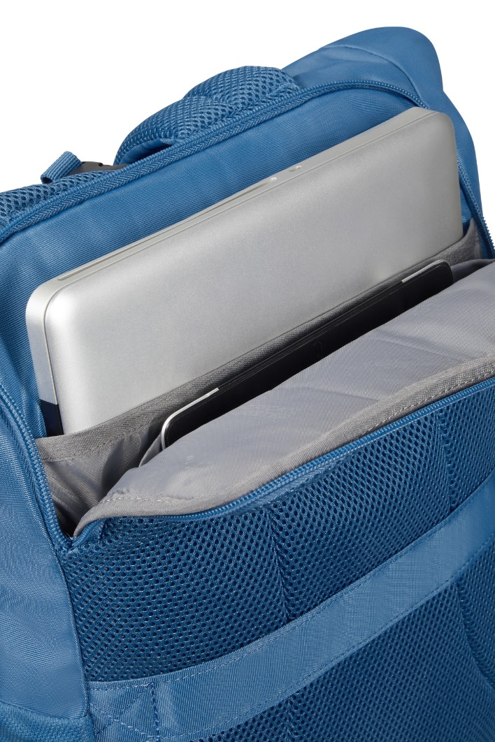 Srebrny laptop jest schowany w wyściełanej kieszeni niebieskiego plecaka.