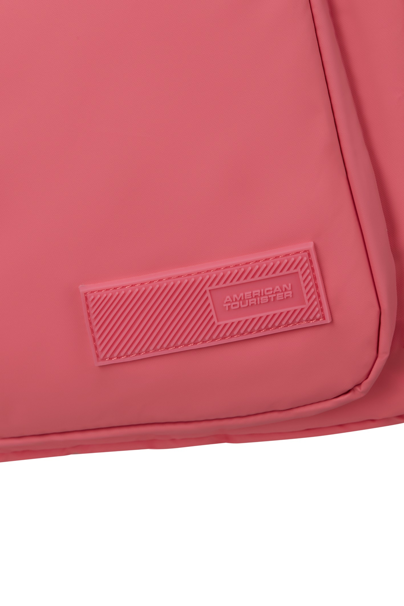 Zbliżenie różowej torby z wytłoczonym logo American Tourister na teksturowanej naszywce.