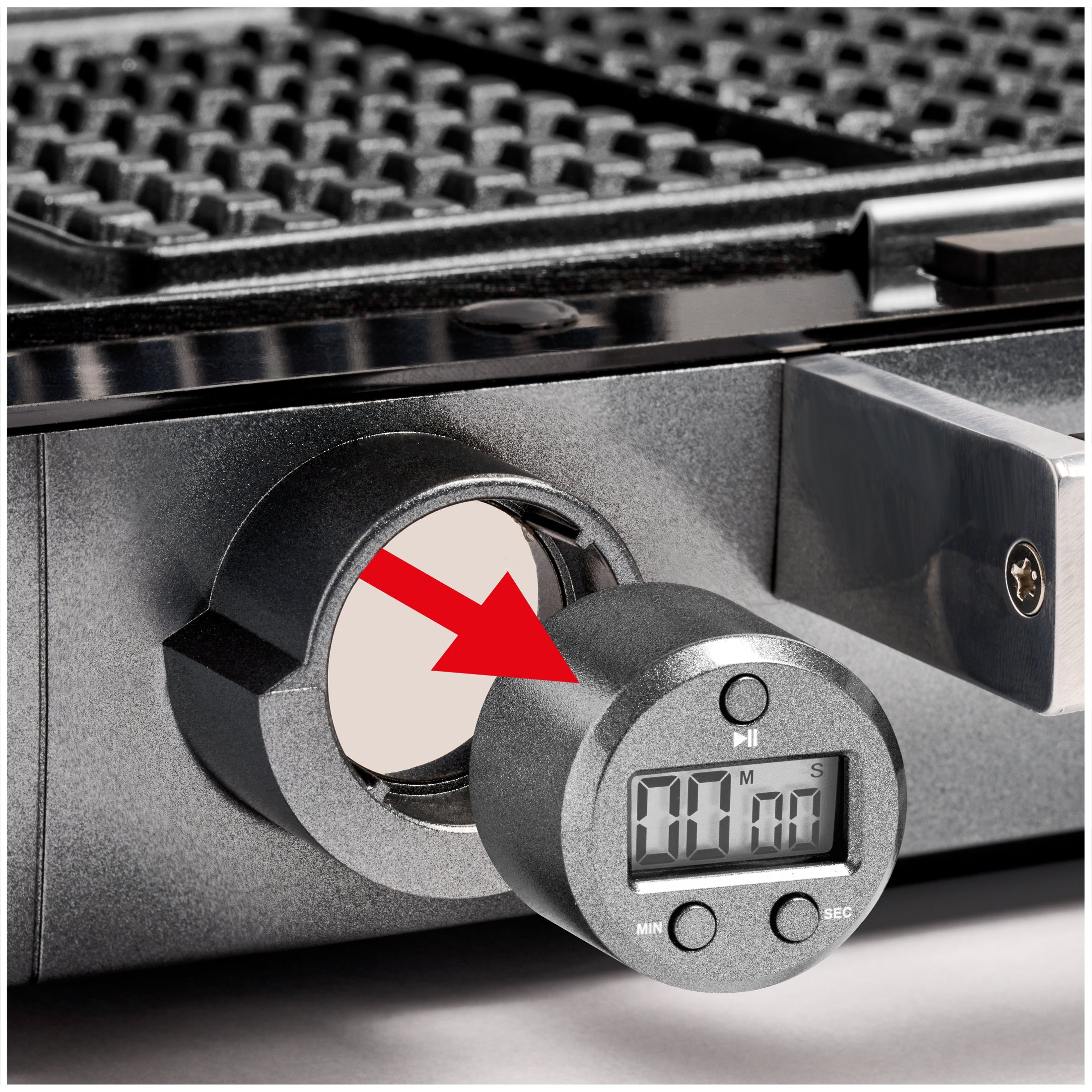 Un timer digitale viene inserito in una piastra per waffle, indicato da una freccia.