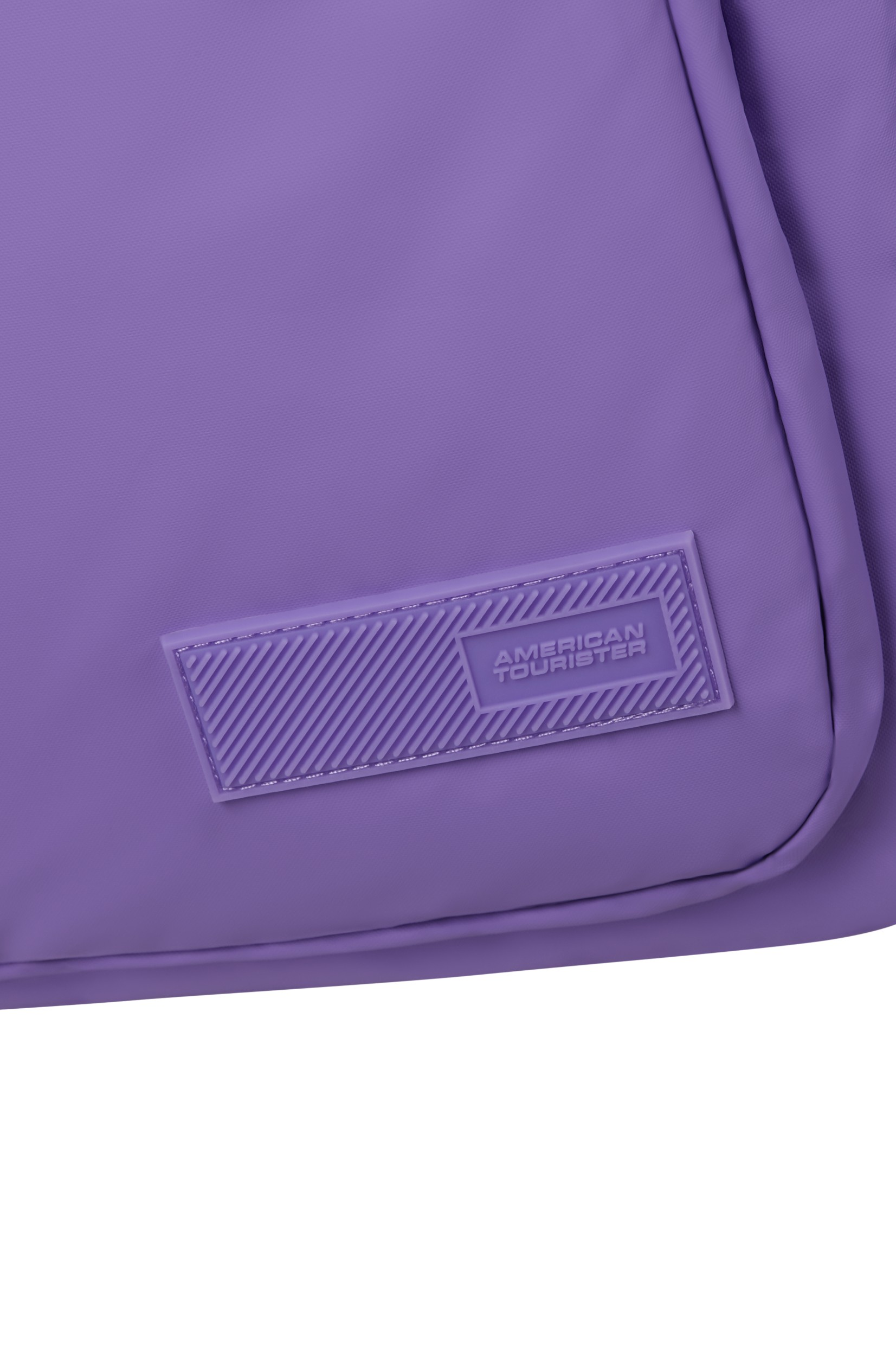 Zbliżenie fioletowej torby z logo American Tourister na gumowej naszywce.