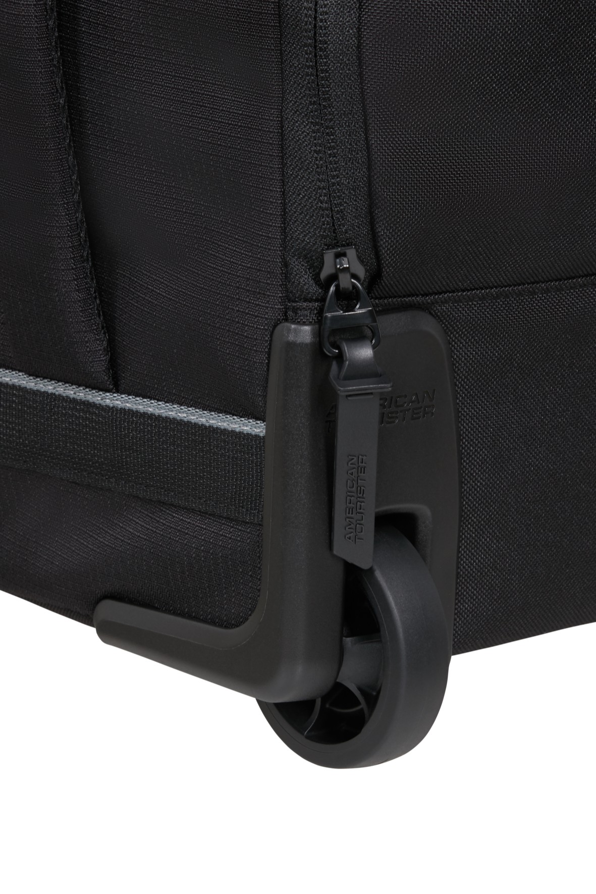 Zbliżenie koła czarnej walizki, uchwytu suwaka z logo American Tourister i fakturowanej tkaniny.