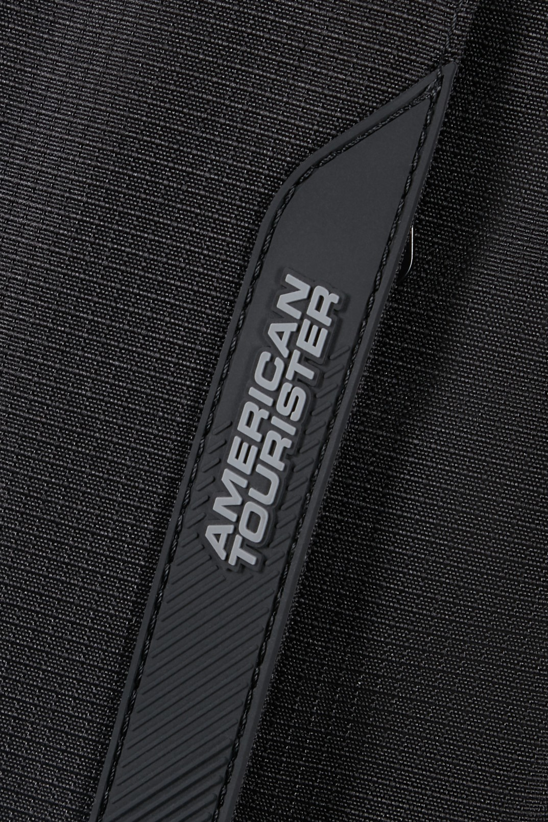 Zbliżenie na czarny, teksturowany pasek z szarym logo American Tourister.