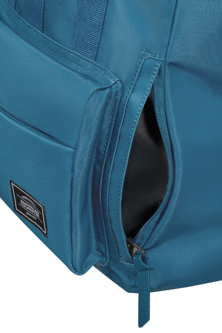 Zbliżenie niebieskiego plecaka z otwartą kieszenią zapinaną na zamek i logo American Tourister.