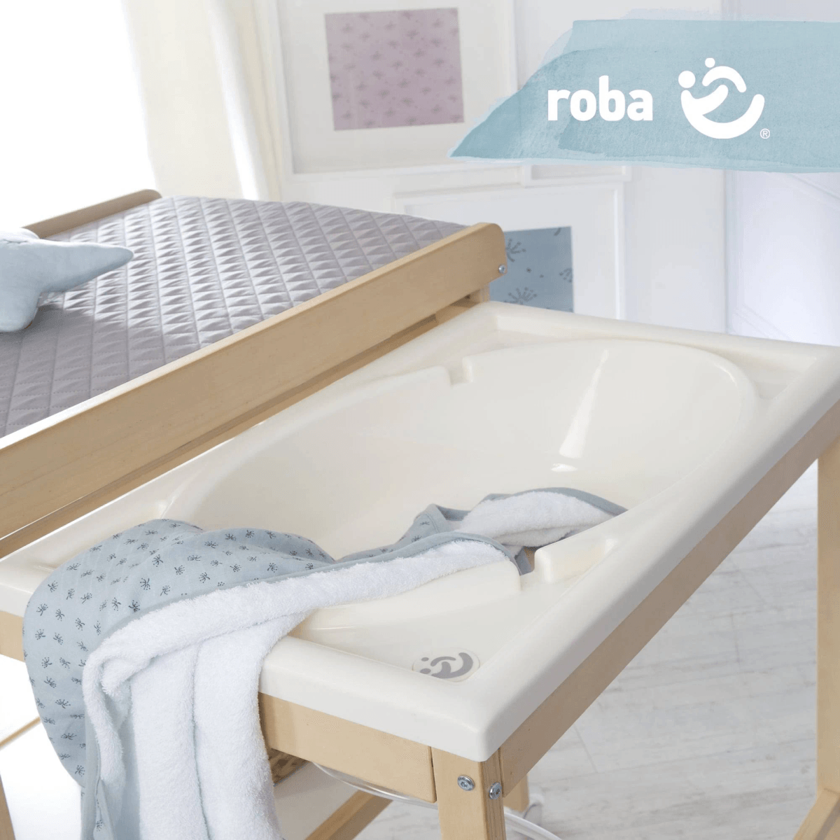 Un cambiador de madera con una bañera blanca deslizable y una toalla azul estampada.