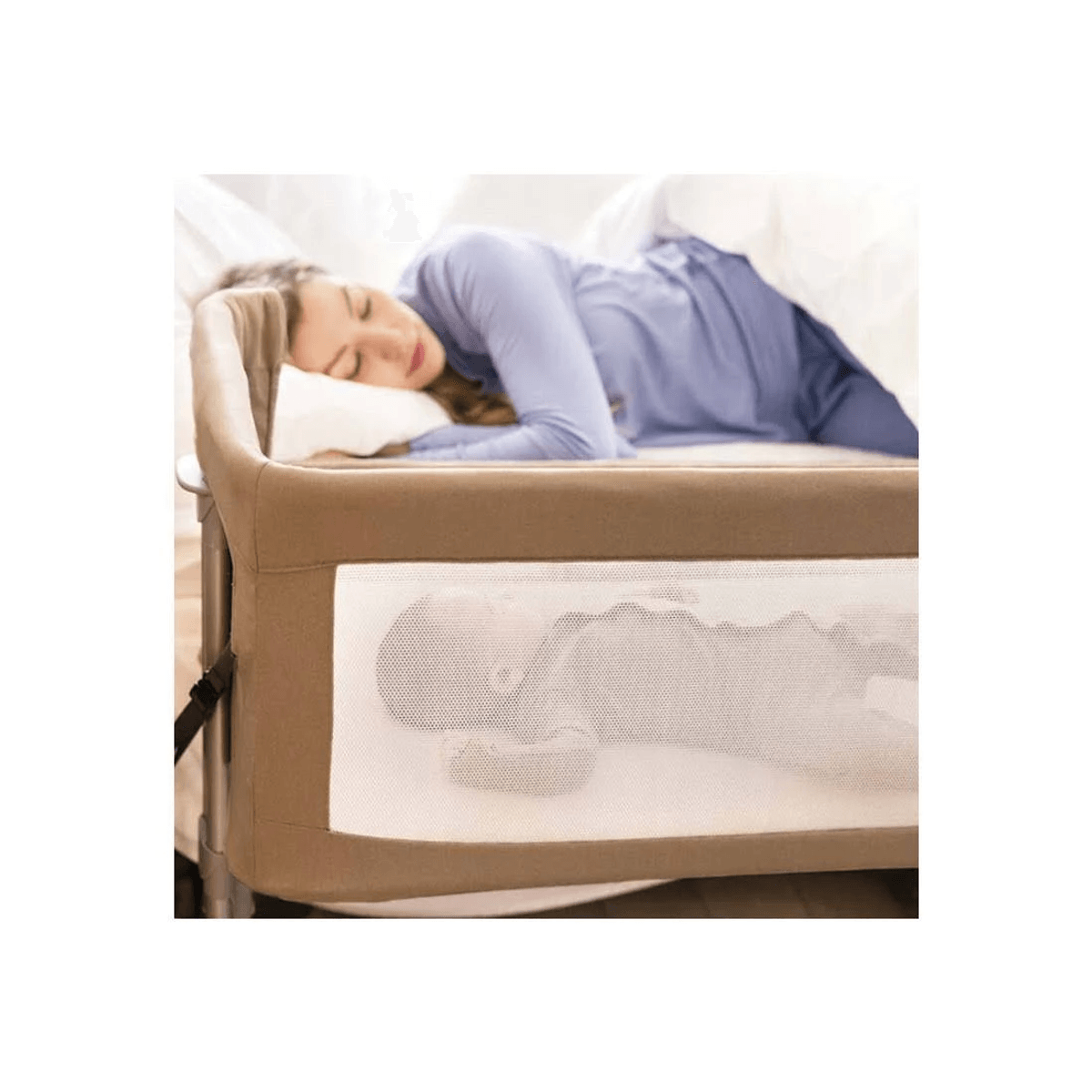 Una madre duerme en una cama junto a una cuna con un bebé durmiendo visible a través de la malla.