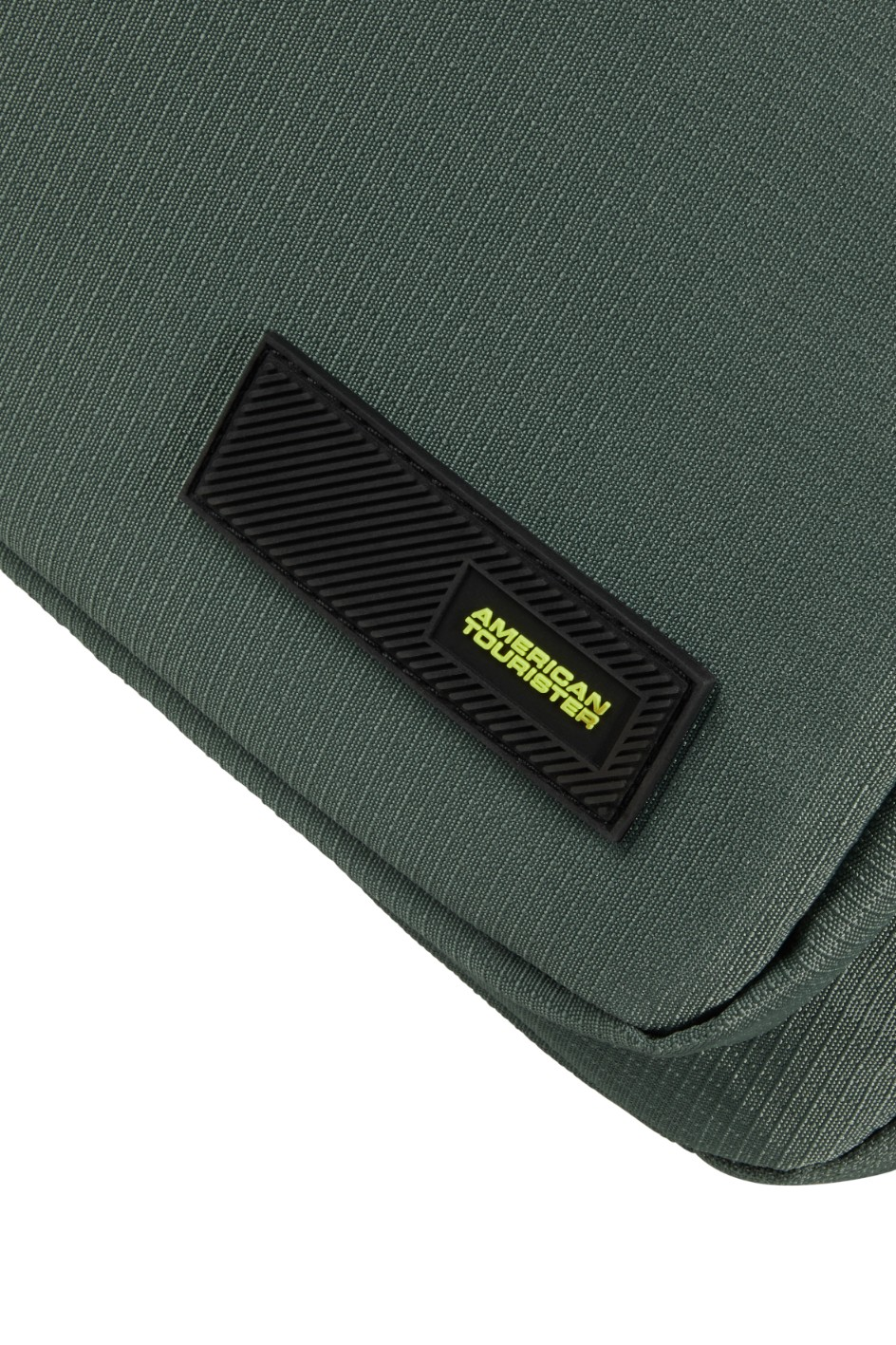 Zbliżenie zielonej torby z czarną naszywką z logo American Tourister z przodu.
