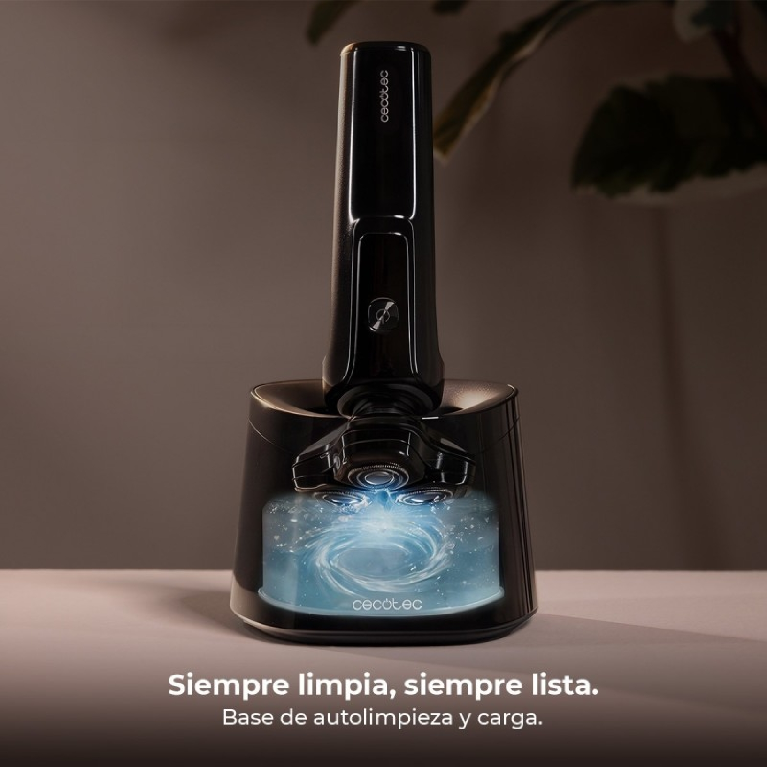 Afeitadora negra en una base de limpieza y carga iluminada sobre una mesa.