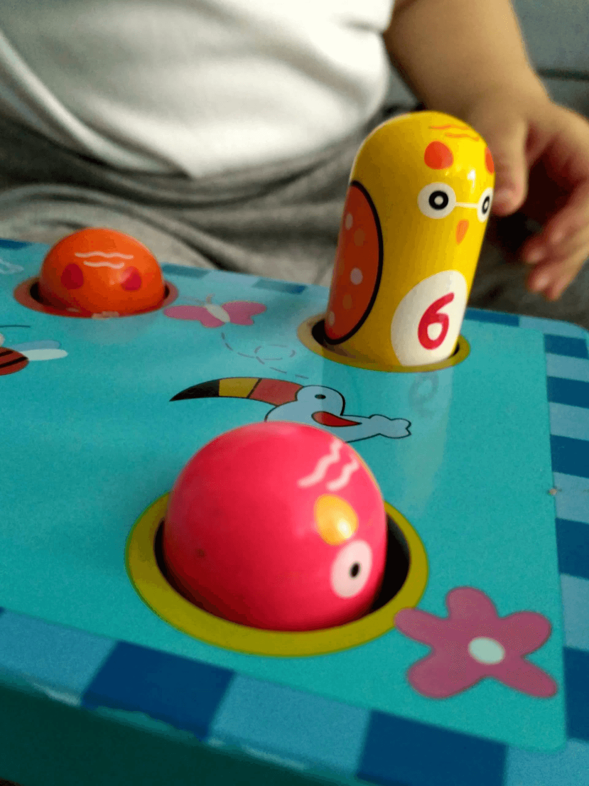 Un niño juega con un juguete azul con figuras de animales coloridas.
