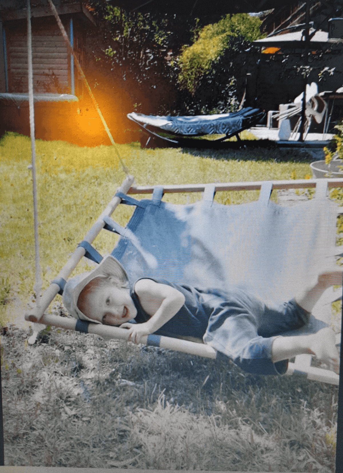 Un niño relajado en una hamaca azul en un jardín soleado.