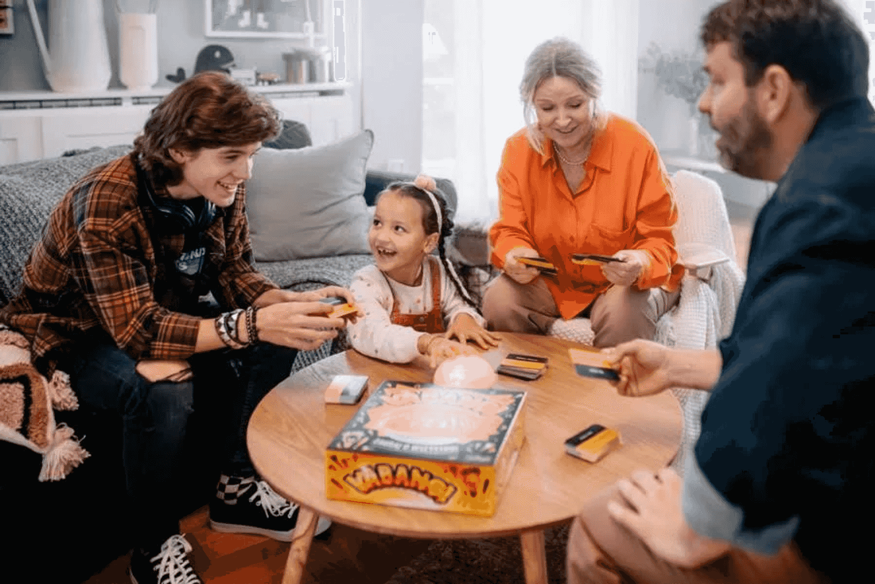 Una familia ríe junta mientras juega a un juego de mesa alrededor de una mesa de centro.