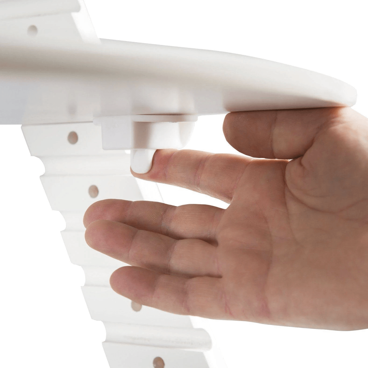 Una mano presiona el botón de liberación debajo de una mesa blanca.