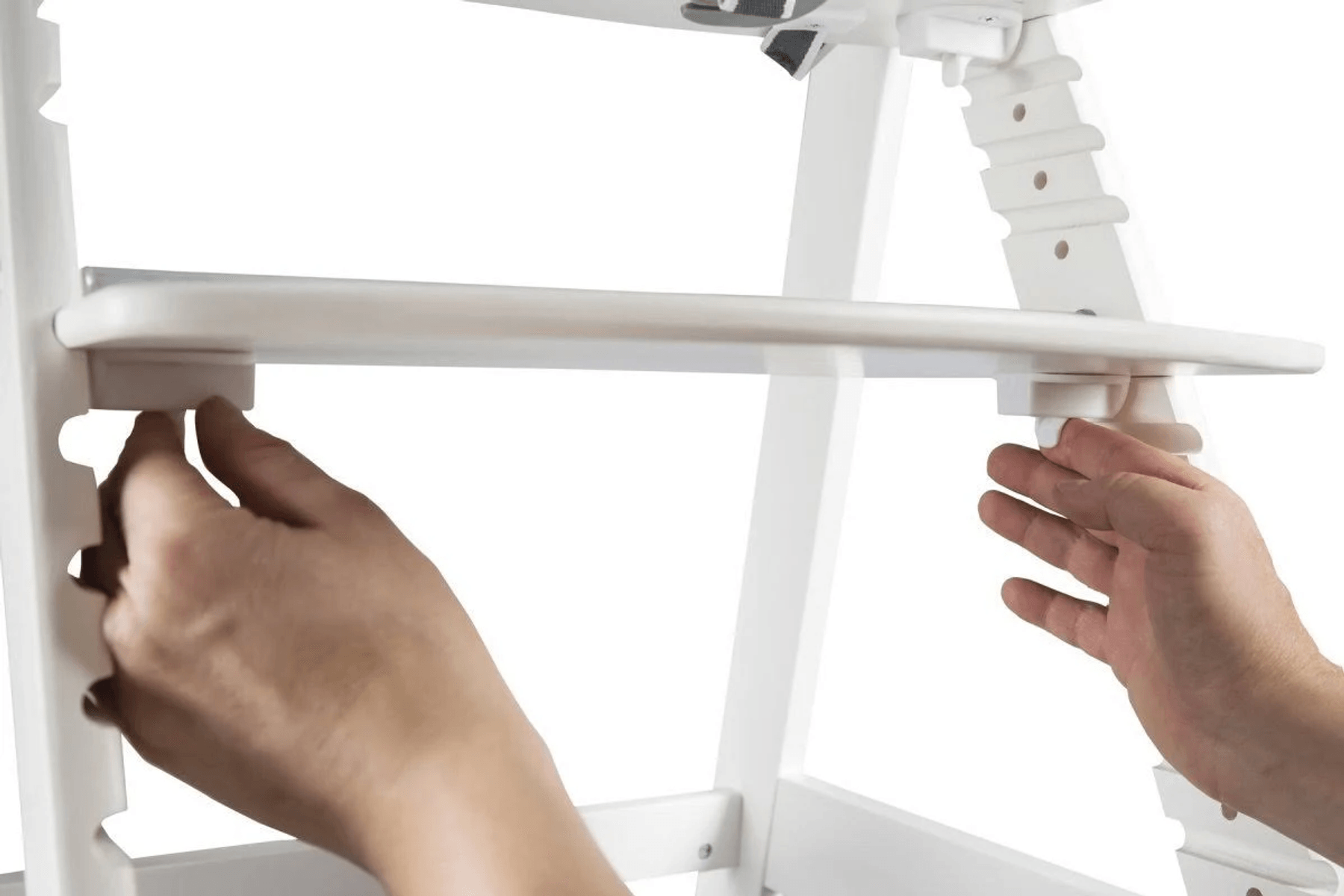 Manos ensamblan un elemento de madera blanca en una silla.
