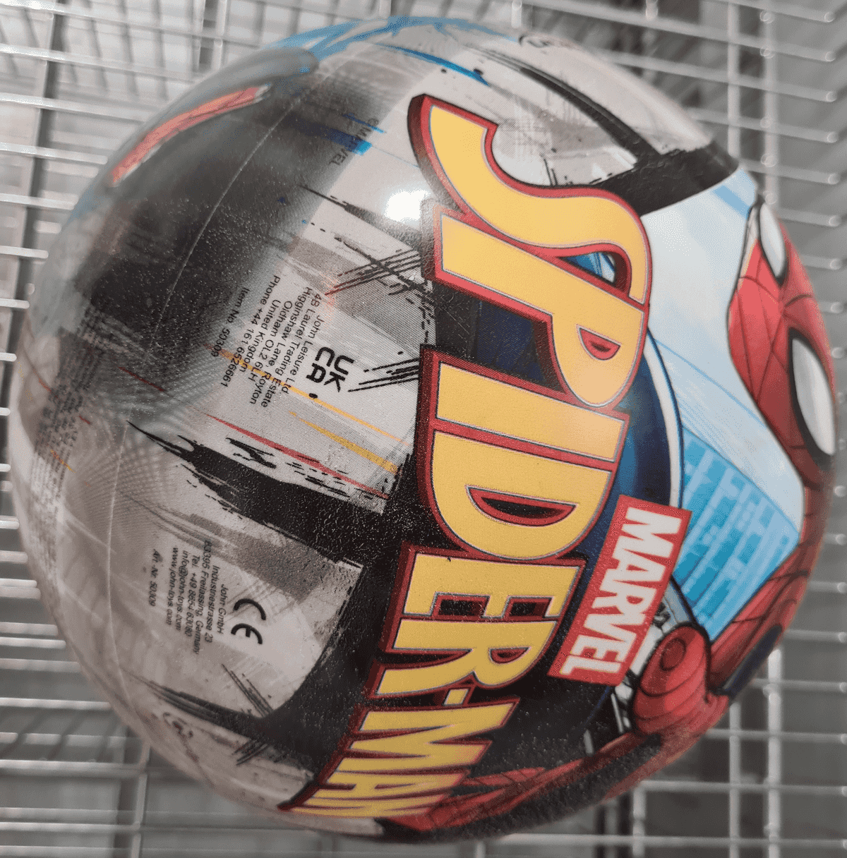 Un balón redondo de Spider-Man con letras amarillas grandes y gráficos de cómics en una rejilla.