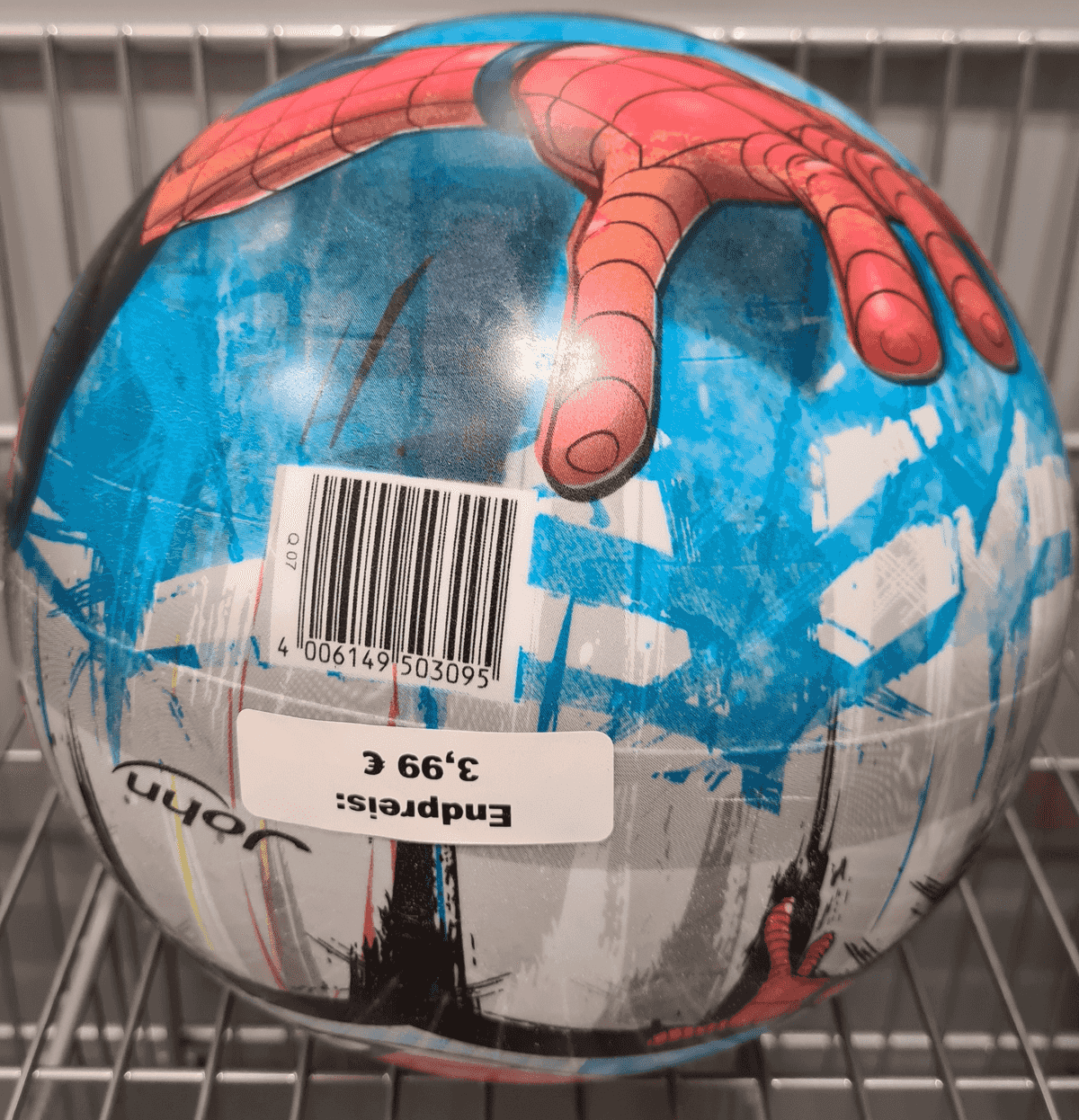 Un balón azul y blanco con diseño de Spiderman, código de barras y etiqueta de precio de 3,99 € en una estantería.