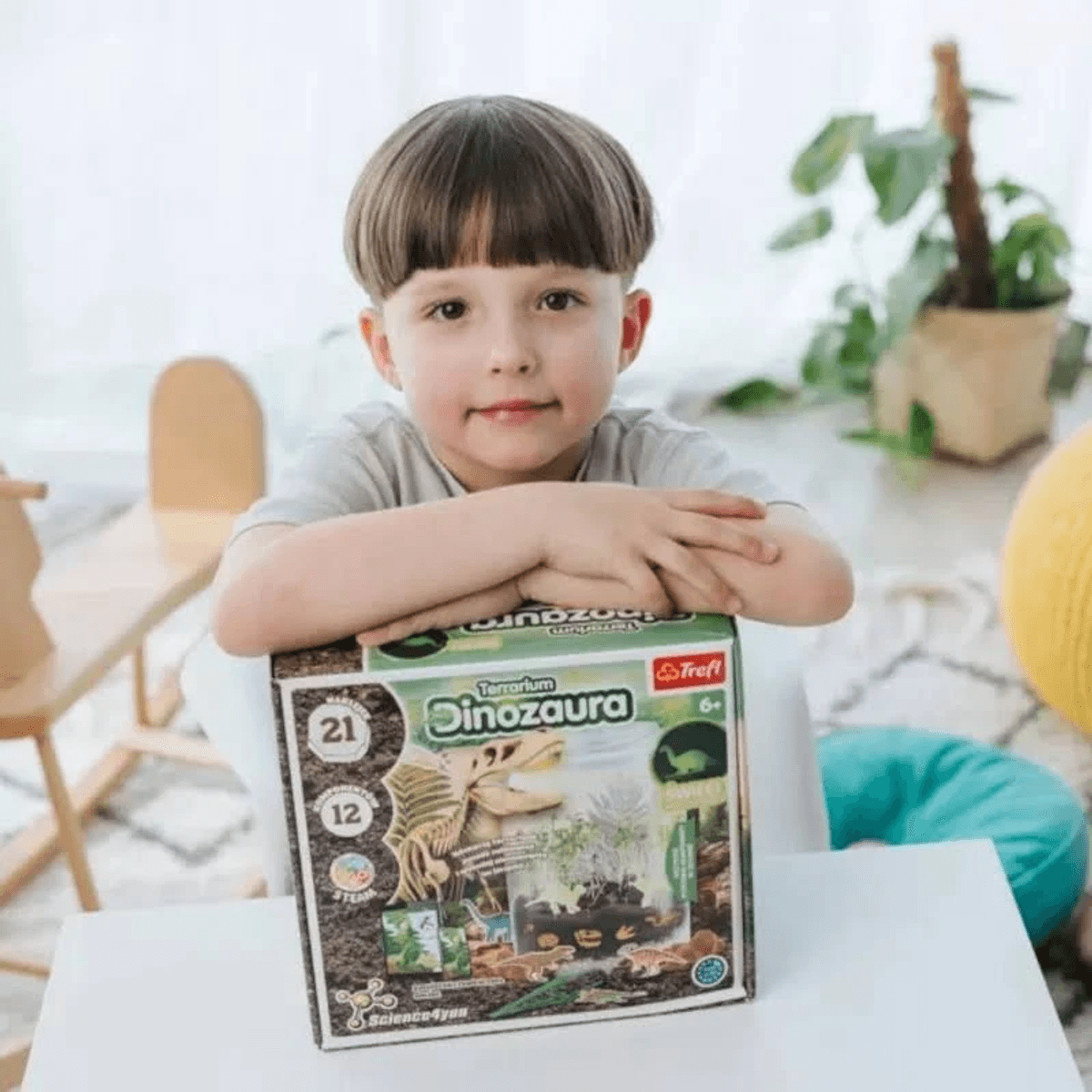 Un niño posando con una caja de juguetes de dinosaurio.
