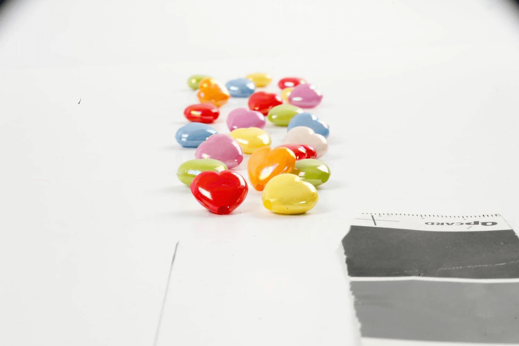 Cuentas coloridas en forma de corazón esparcidas sobre un fondo blanco.