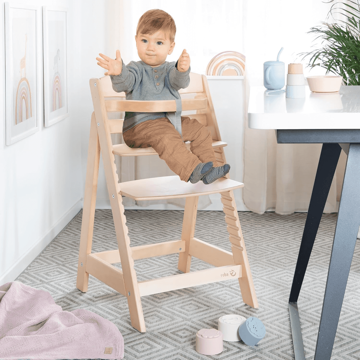 Un niño pequeño se sienta en una trona de madera en una habitación luminosa.
