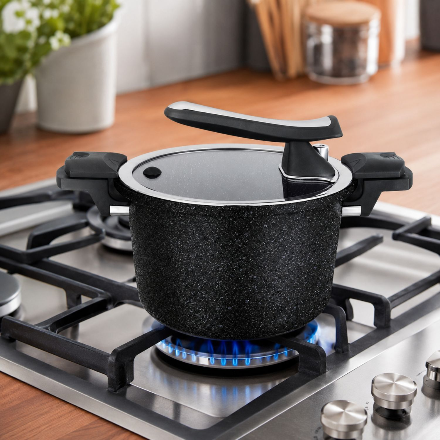 Una pentola a pressione nera si trova su un piano cottura a gas acceso in una cucina.