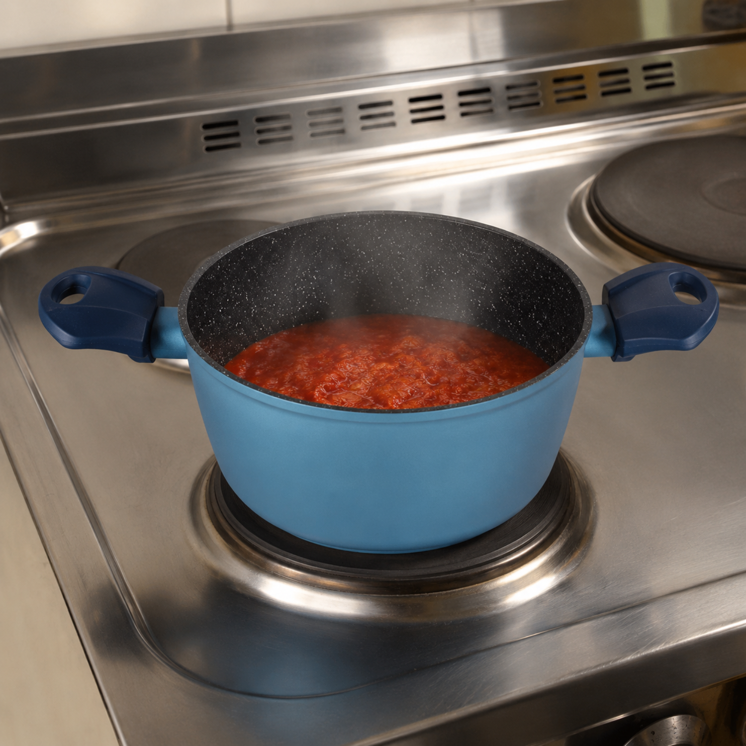 Una pentola blu con salsa di pomodoro rossa bolle su un piano cottura elettrico.