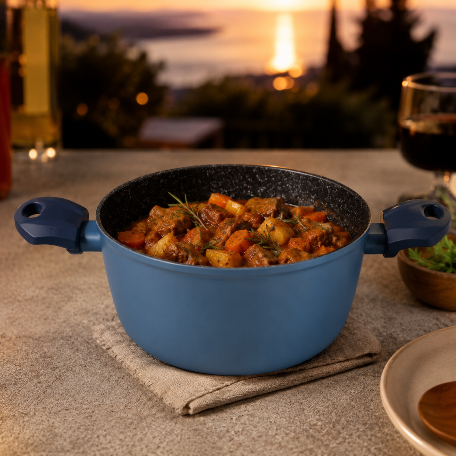 Una pentola blu piena di stufato di carne, patate e carote su un tavolo all'aperto al tramonto.