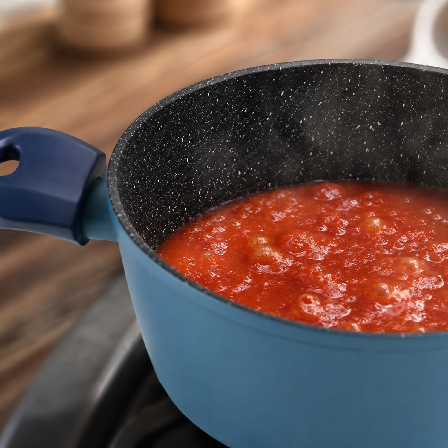 Una padella blu con salsa di pomodoro rossa bollente sul fuoco.