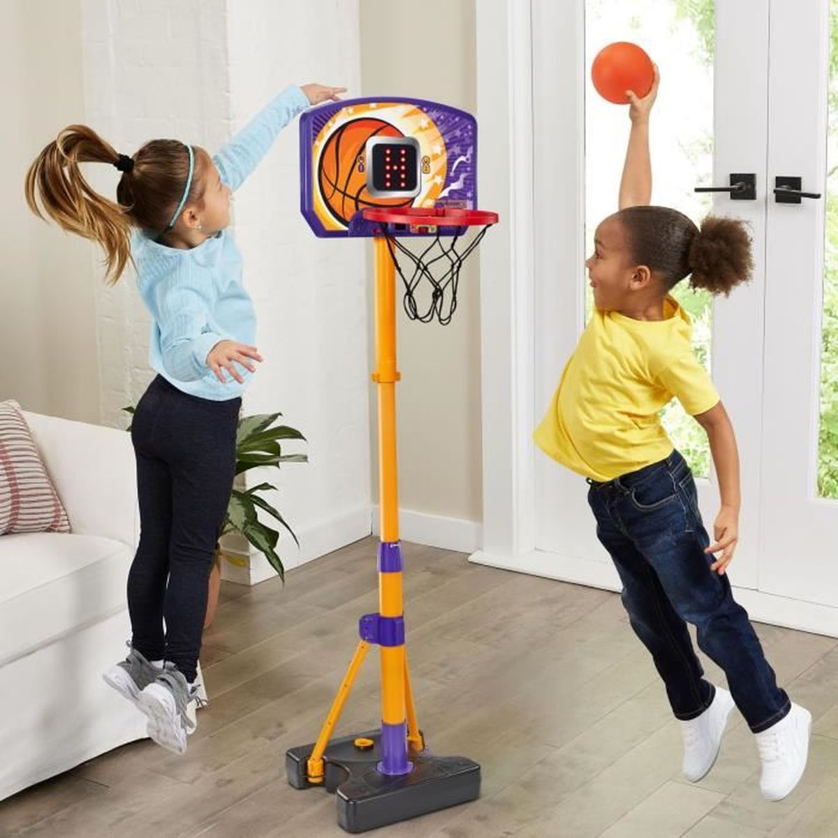 Due bambine giocano a basket in casa con un canestro regolabile.