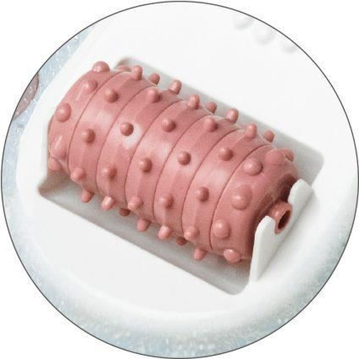 Ein rosafarbener Fußmassageroller mit kleinen Noppen, eingebettet in ein weißes Plastikgehäuse.