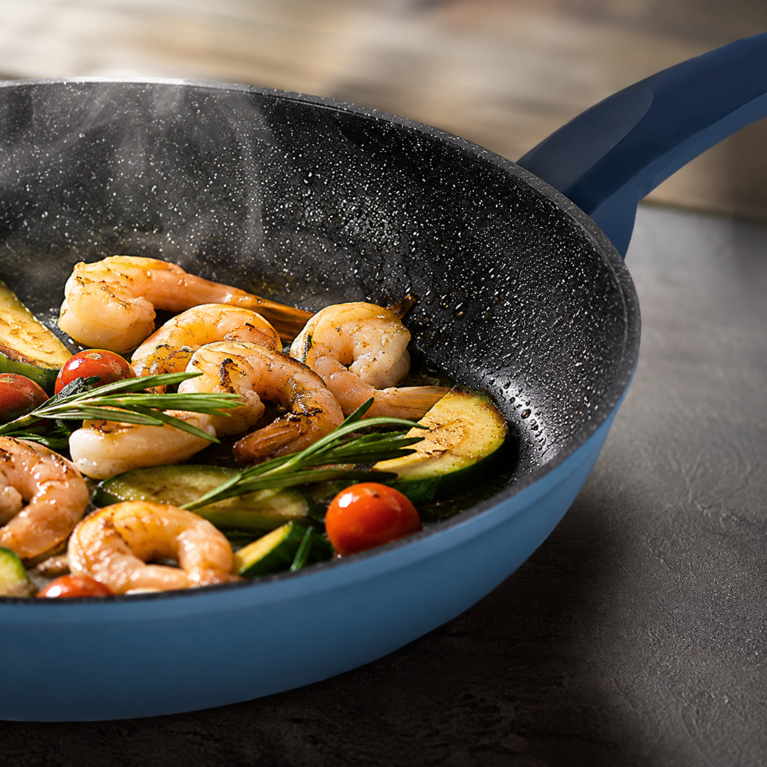 Gamberi, zucchine e pomodorini sfrigolano in una padella blu con rosmarino.