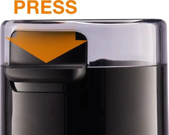 Czarny młynek do kawy z przezroczystą pokrywką, napisem PRESS i pomarańczową strzałką w dół.