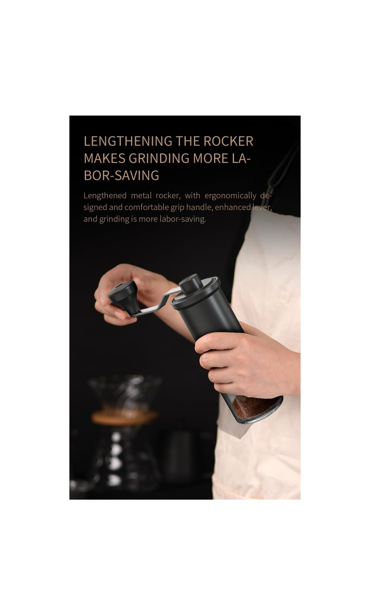 Person bedient eine schwarze Kaffeemühle mit verlängerter Handkurbel vor dunklem Hintergrund.