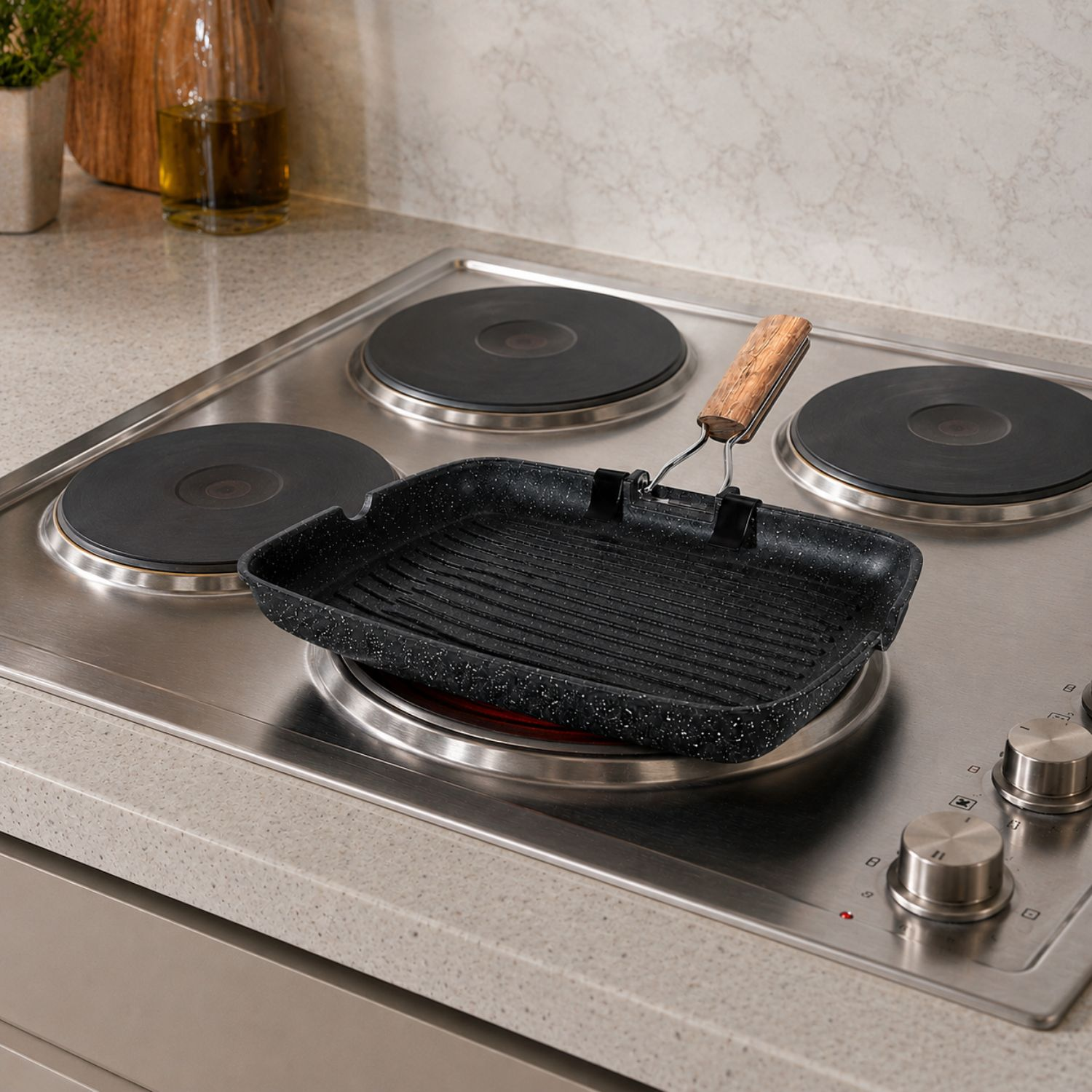 Una padella per grill nera con manico in legno si trova su un moderno piano cottura in acciaio inox.
