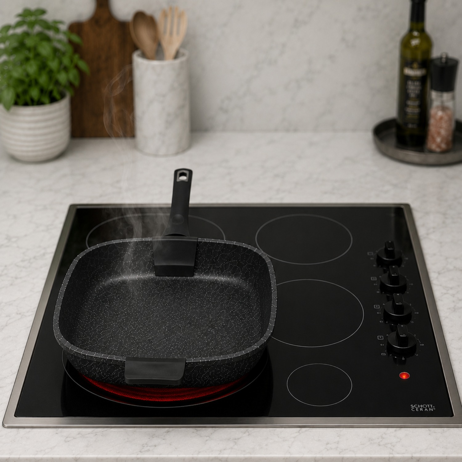 Una padella quadrata calda e fumante è su un piano cottura in vetroceramica, con accessori da cucina sullo sfondo.