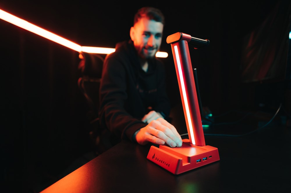 Un uomo in una stanza buia tocca un supporto per cuffie rosso luminoso.