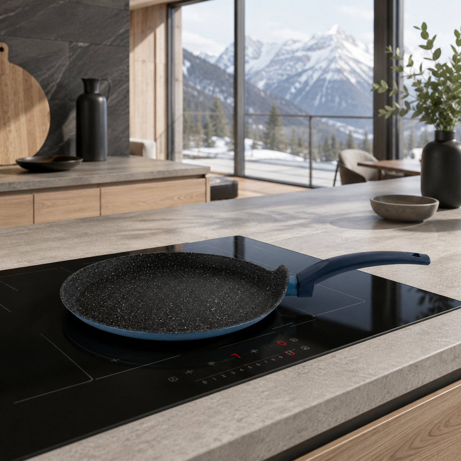 Una padella nera poggia su un piano cottura a induzione in una cucina moderna con vista sulle montagne.