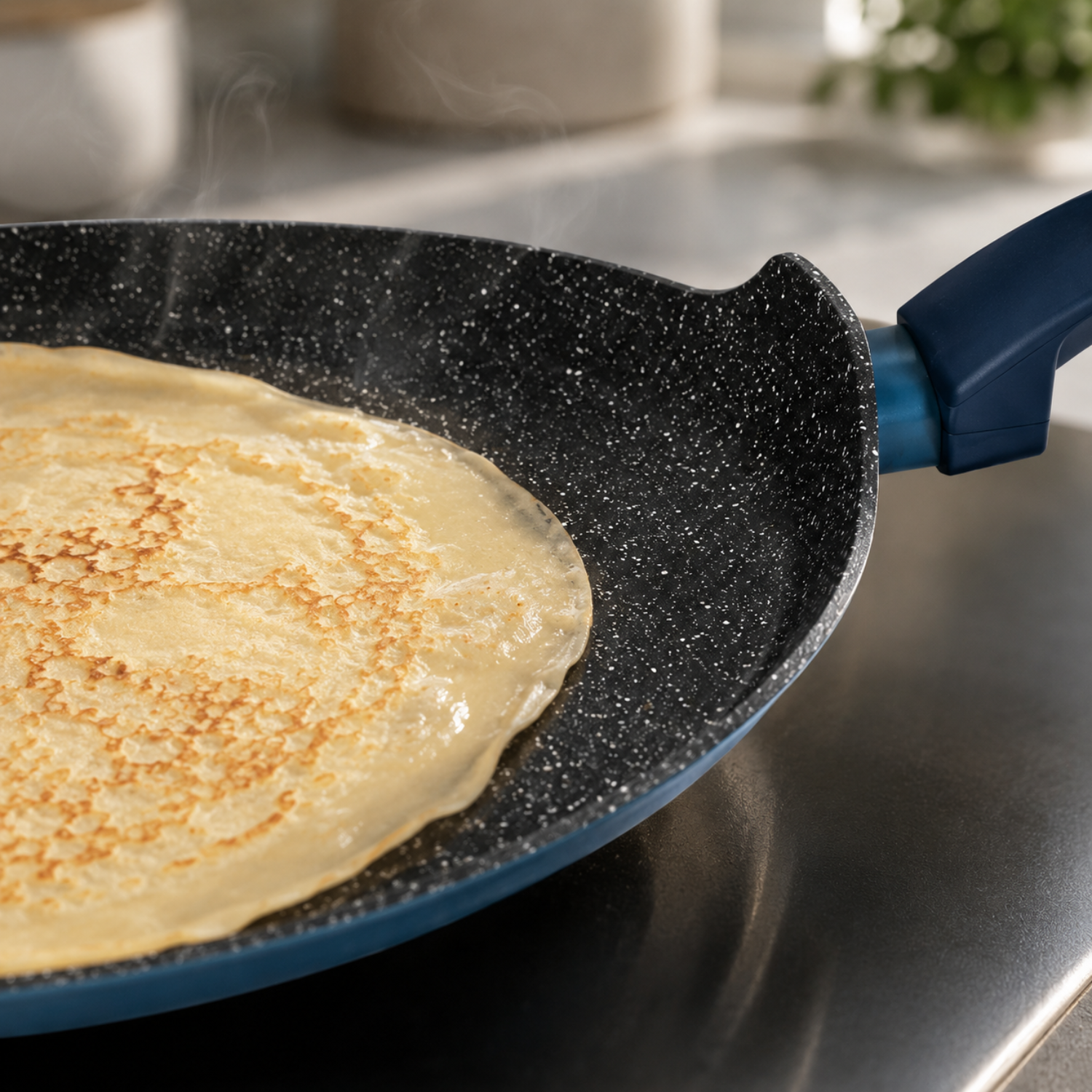 Una crepe cuoce in una padella nera maculata con vapore, sui fornelli.