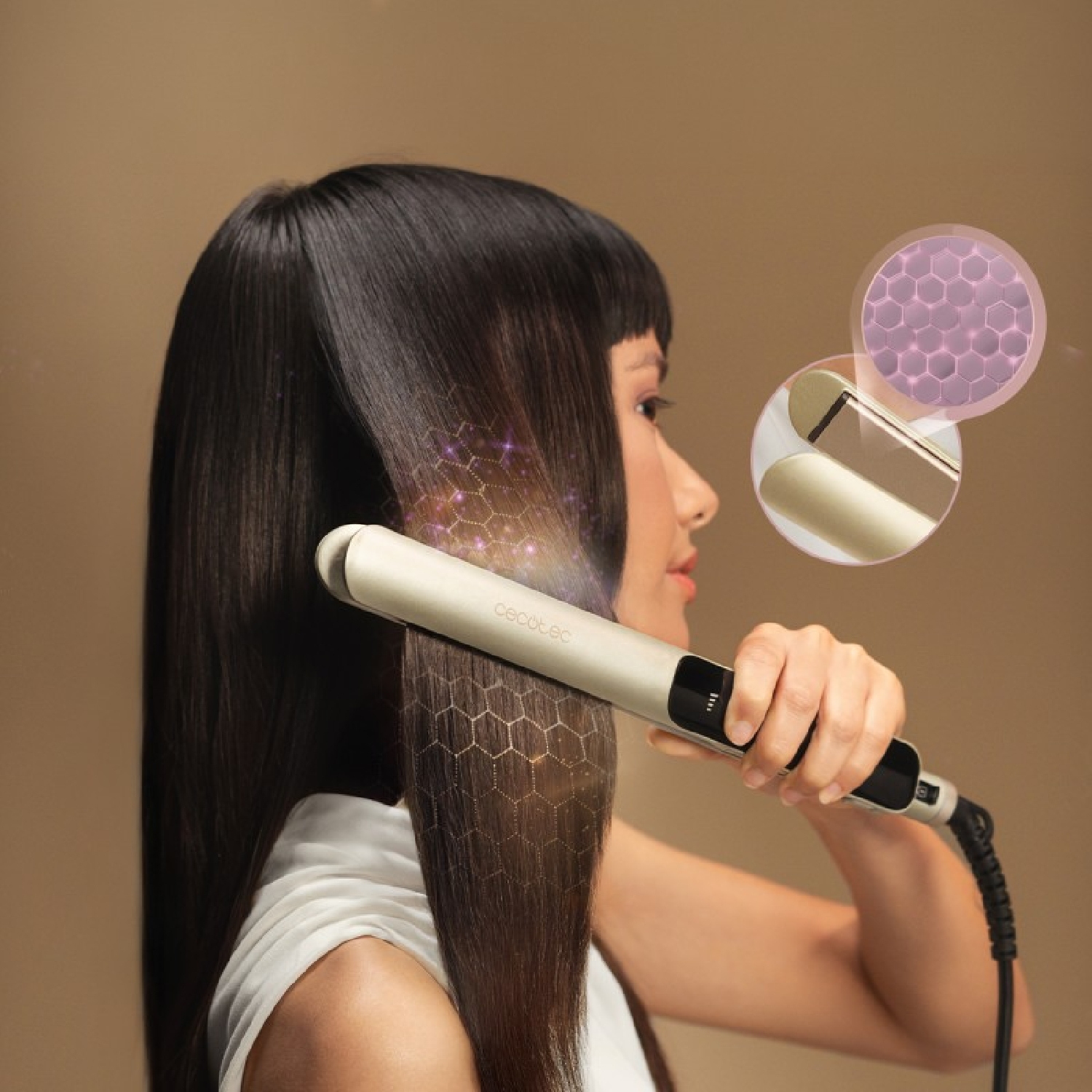 Una donna liscia i suoi lunghi capelli scuri con una piastra dorata.