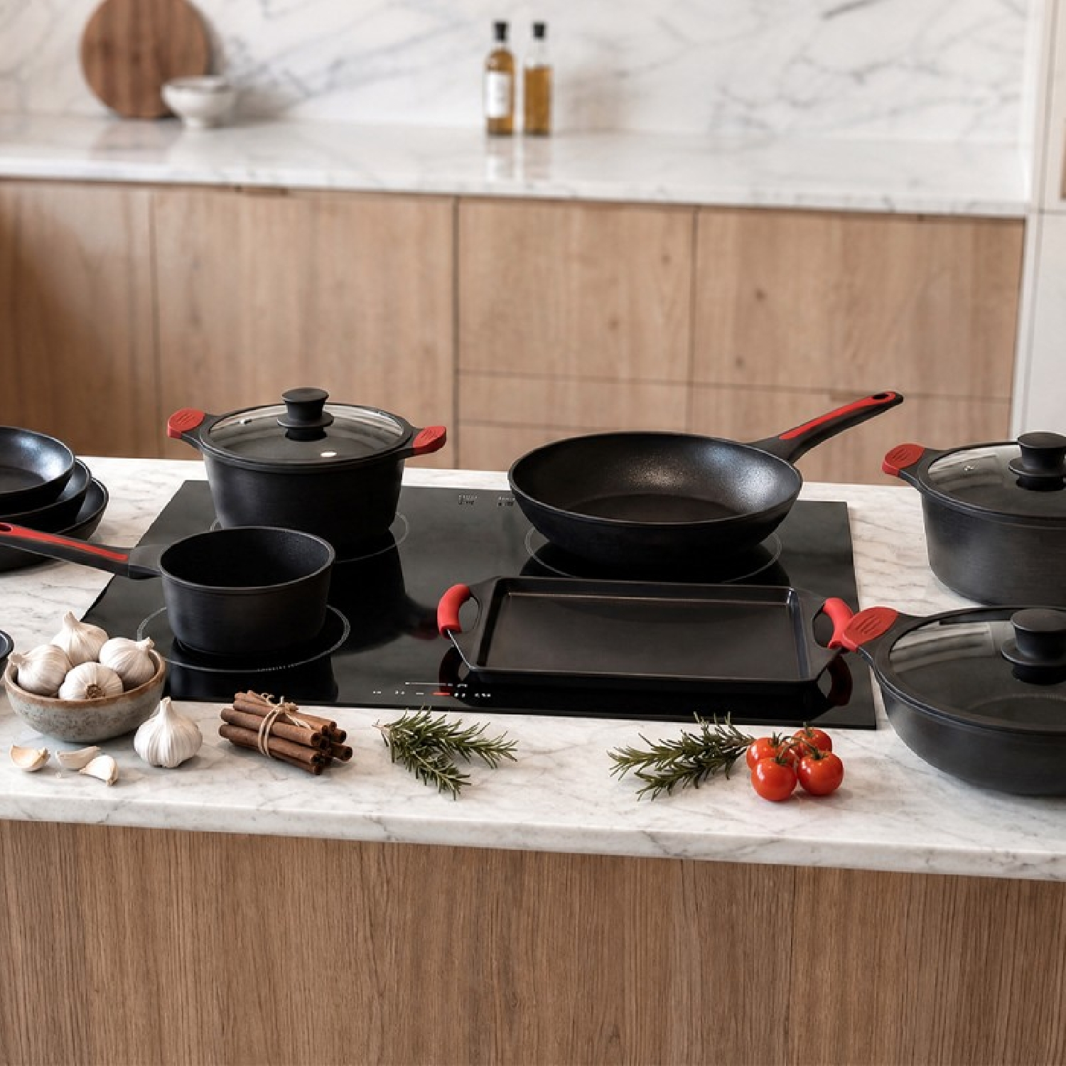 Menaje de cocina negro con detalles rojos en una estufa en una cocina moderna, rodeado de ajo y especias.