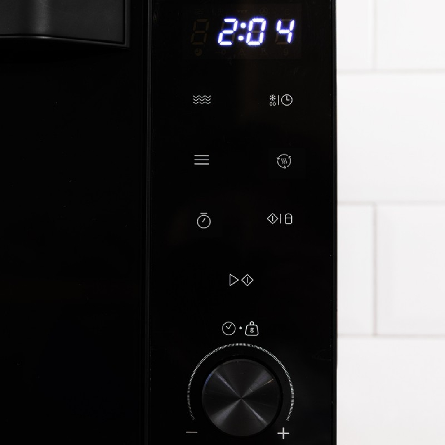 Panel de control negro con pantalla digital que muestra 2:04, botones táctiles y perilla giratoria.