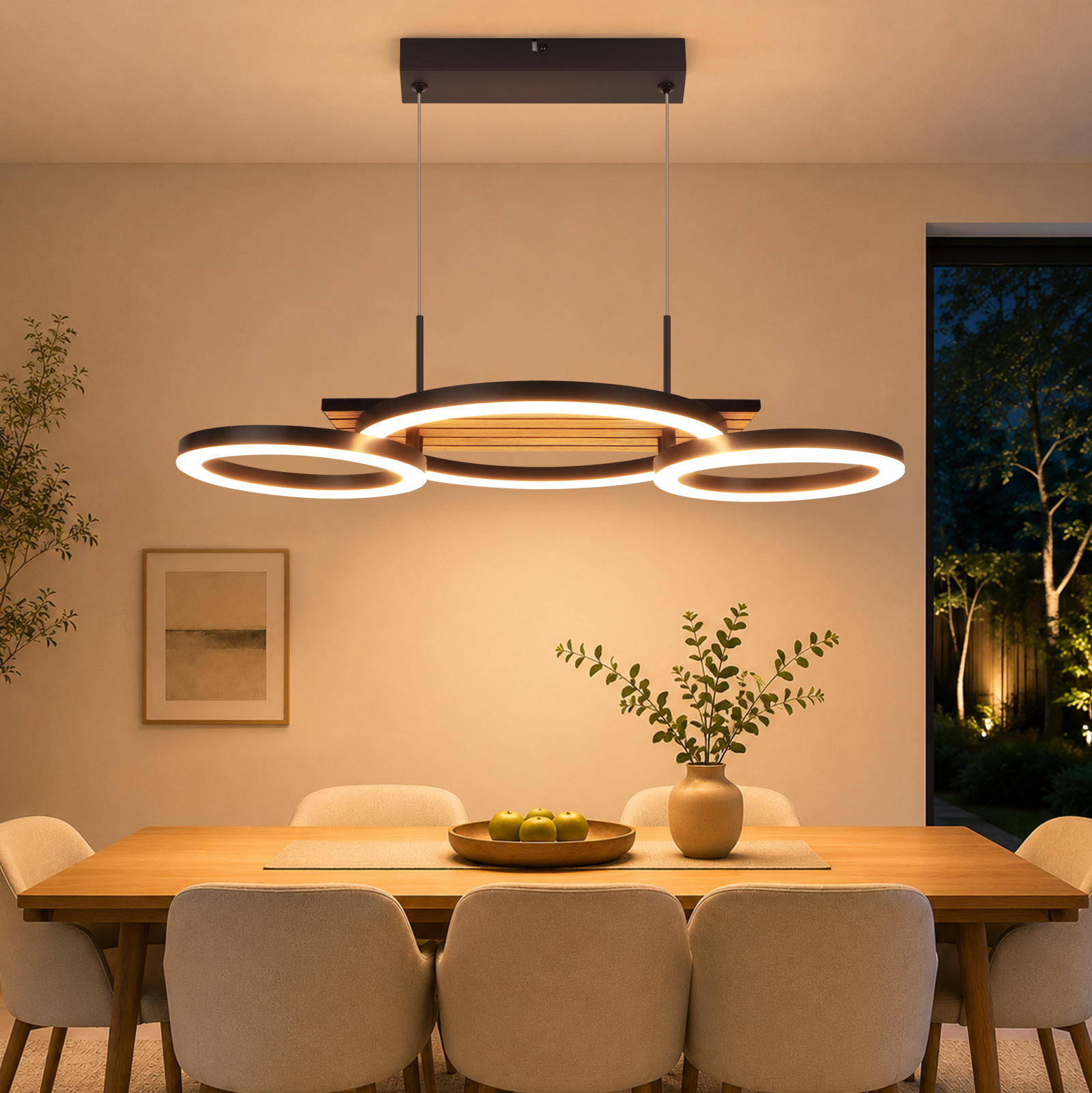 Una moderna lámpara colgante LED de tres anillos cuelga sobre una mesa de comedor con sillas, frutero y jarrón.
