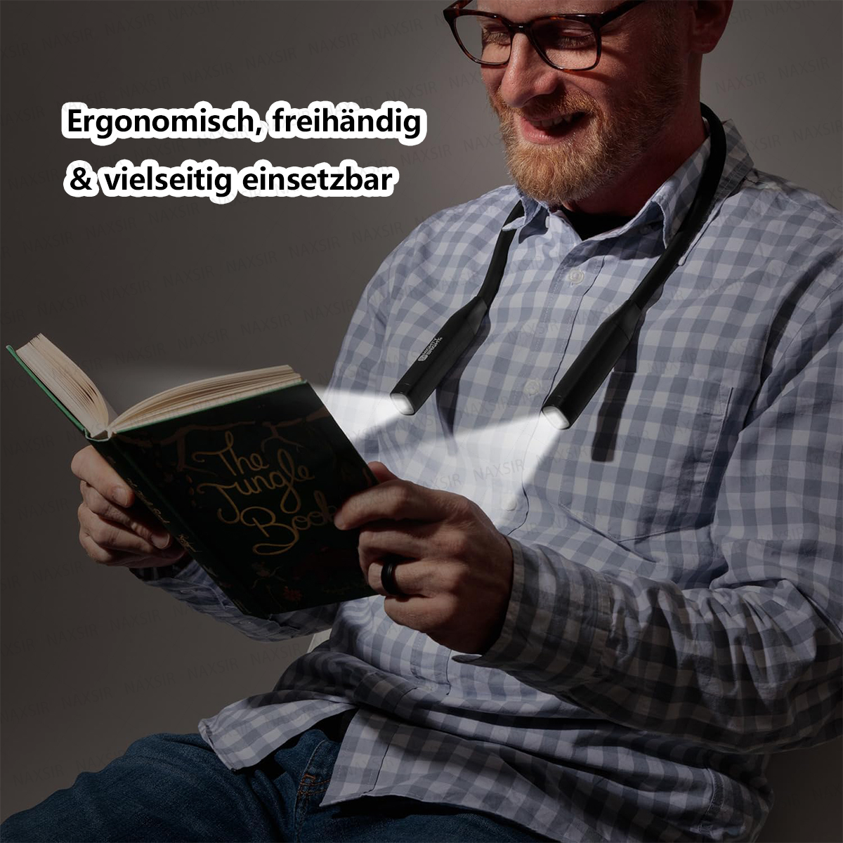 Ein Mann mit Brille trägt eine tragbare Nackenleuchte und liest im Dunkeln ein Buch.