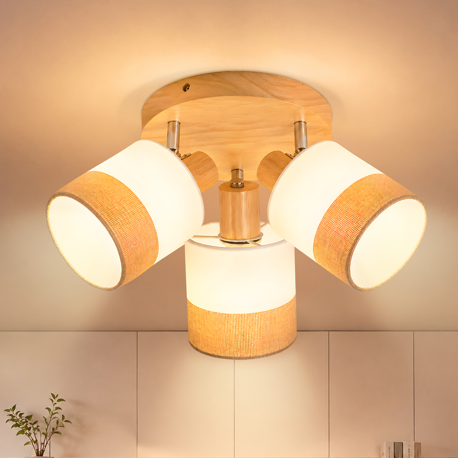 Una lámpara de techo con tres pantallas cilíndricas de madera y tela blanca, que emite luz cálida.