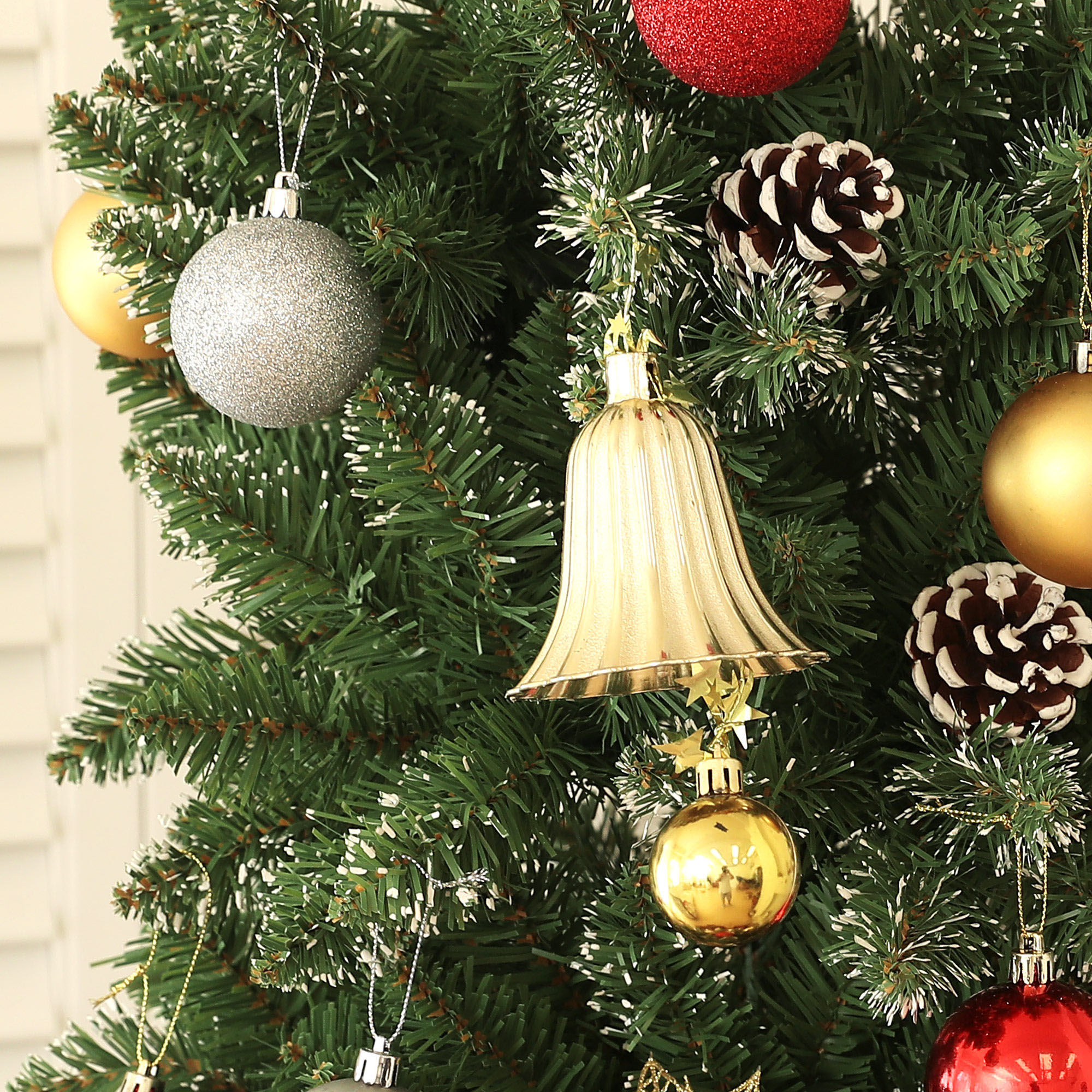 Un árbol de navidad decorado con bolas de oro y plata, una campana y piñas.
