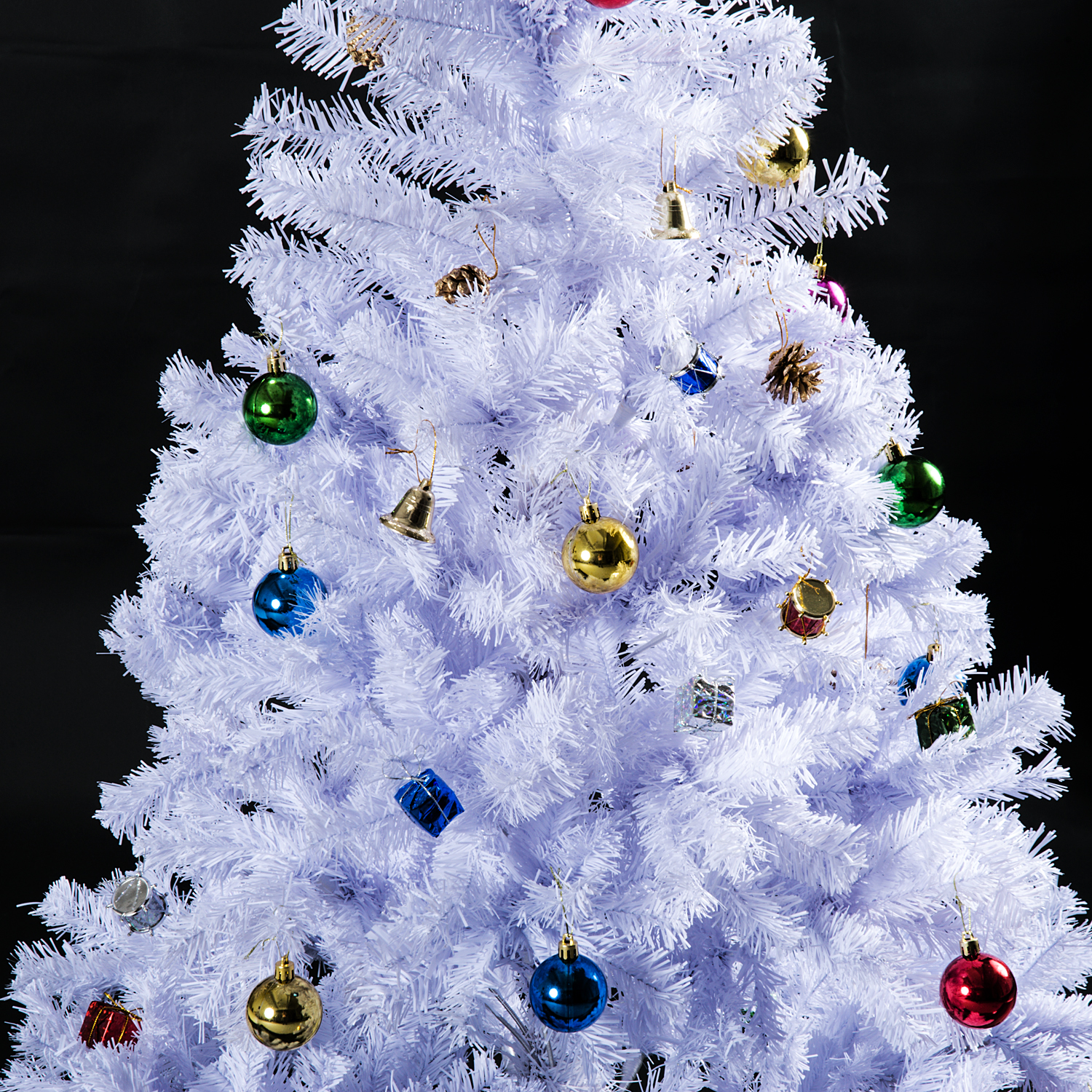 Un árbol de Navidad blanco decorado con adornos de colores y campanas sobre fondo oscuro.