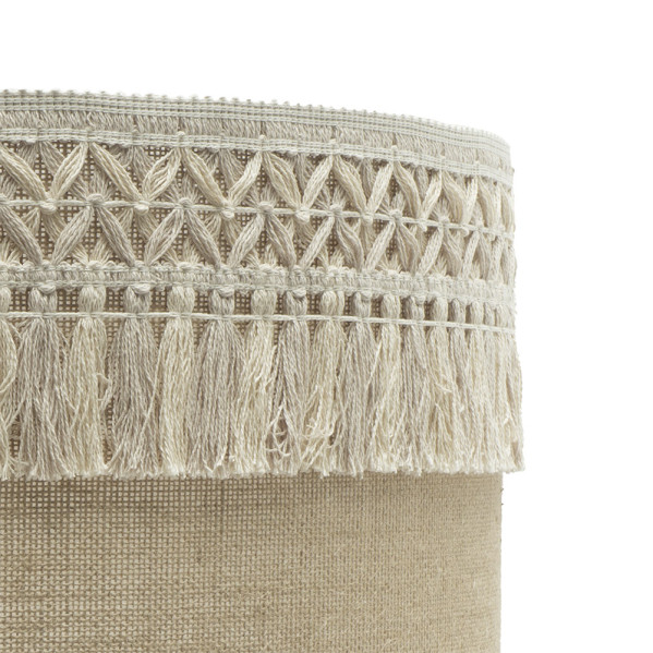 Pantalla de lámpara de lino beige con ribete de macramé decorativo y flecos sobre fondo blanco.