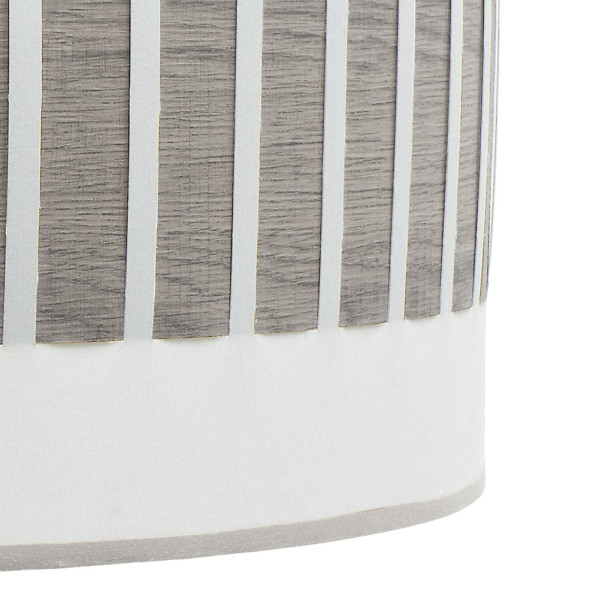 Primer plano de una lámpara cilíndrica con lamas de madera gris y base blanca sobre fondo blanco.